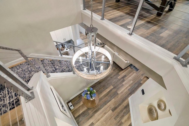 stairs featuring a high ceiling, wood finished floors, and a notable chandelier