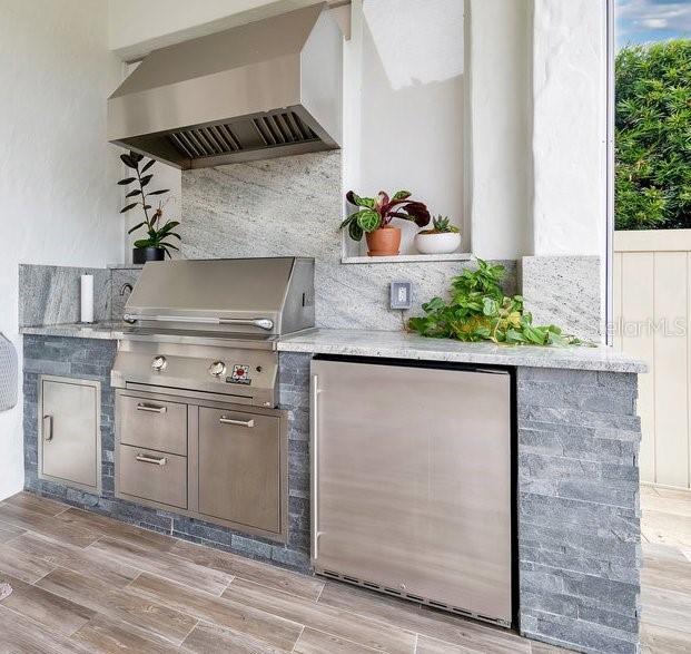 bar featuring wall chimney exhaust hood, wood finish floors, and freestanding refrigerator