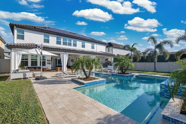 back of house with a patio area, a fenced backyard, a fenced in pool, and solar panels