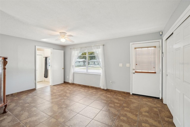 spare room featuring a textured ceiling, ceiling fan, and baseboards