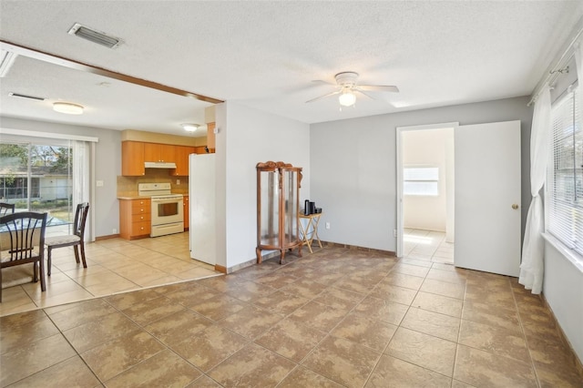 kitchen featuring a textured ceiling, under cabinet range hood, white appliances, visible vents, and light countertops