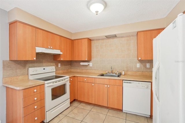 kitchen with white appliances, decorative backsplash, light countertops, under cabinet range hood, and a sink