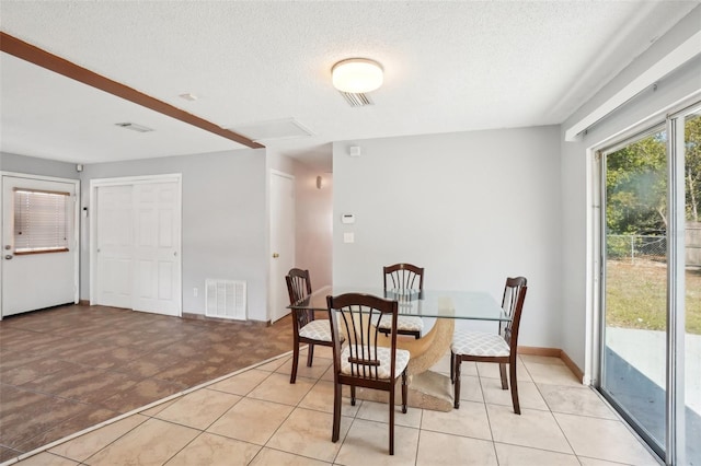 dining area with a textured ceiling, light tile patterned floors, and visible vents