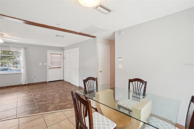 tiled dining area with attic access, baseboards, visible vents, ceiling fan, and a textured ceiling