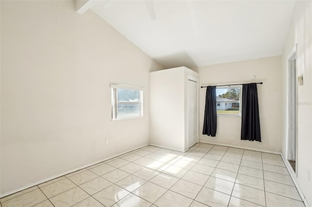 spare room with a healthy amount of sunlight, lofted ceiling with beams, and light tile patterned flooring