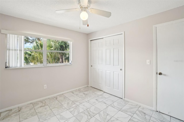 unfurnished bedroom with marble finish floor, a textured ceiling, baseboards, and a closet