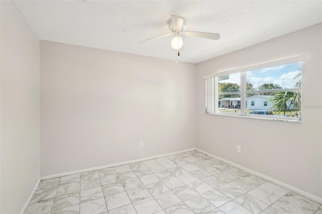 unfurnished room featuring a textured ceiling, marble finish floor, a ceiling fan, and baseboards