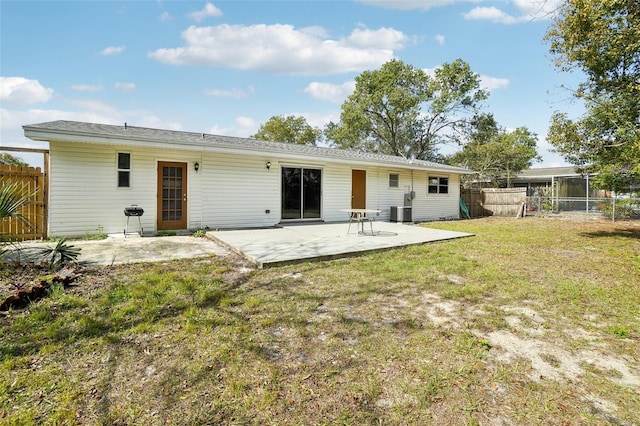 rear view of house with central AC, a lawn, fence, and a patio