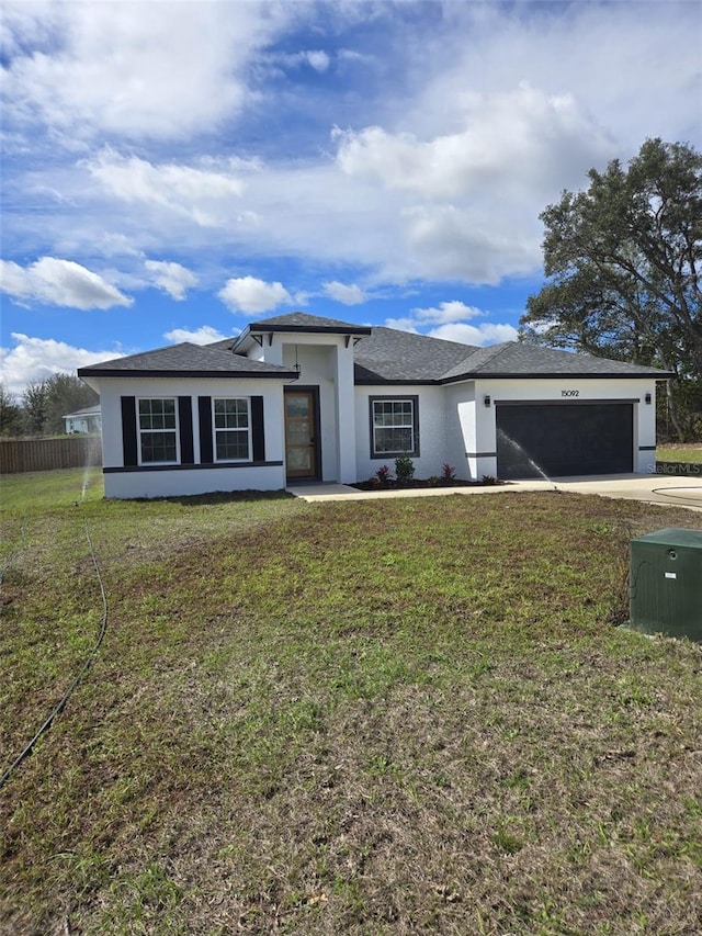 prairie-style house featuring a garage, fence, a front lawn, and stucco siding