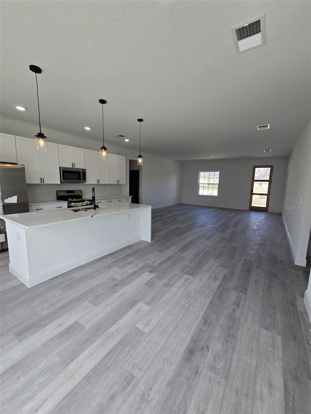 kitchen featuring stainless steel appliances, visible vents, white cabinets, light countertops, and light wood finished floors