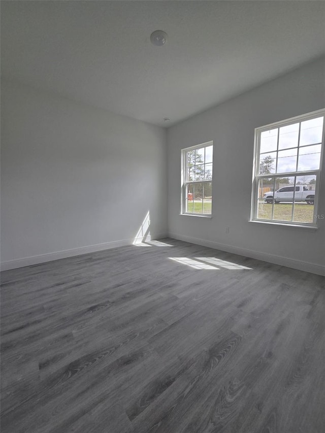 unfurnished room with dark wood finished floors and baseboards