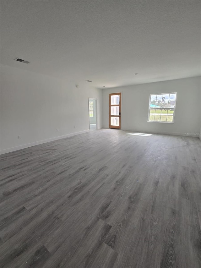 spare room with baseboards, visible vents, dark wood finished floors, and a textured ceiling