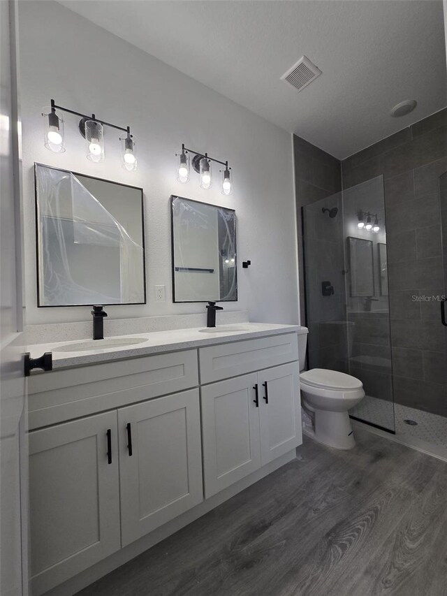 bathroom featuring a stall shower, visible vents, a sink, and wood finished floors