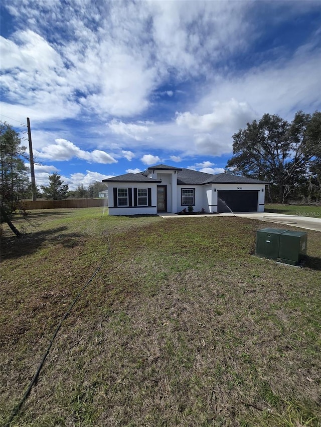 view of front of home featuring stucco siding, concrete driveway, an attached garage, fence, and a front lawn