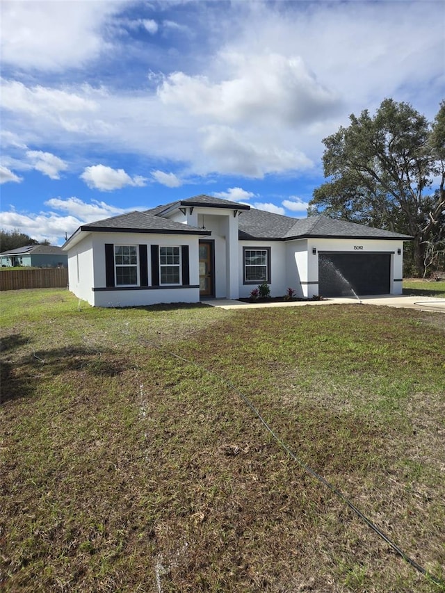 prairie-style house featuring a garage, fence, driveway, stucco siding, and a front lawn