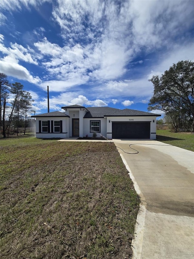 view of front of home with driveway, an attached garage, a front yard, and stucco siding