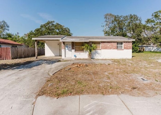 ranch-style house with driveway, fence, and brick siding