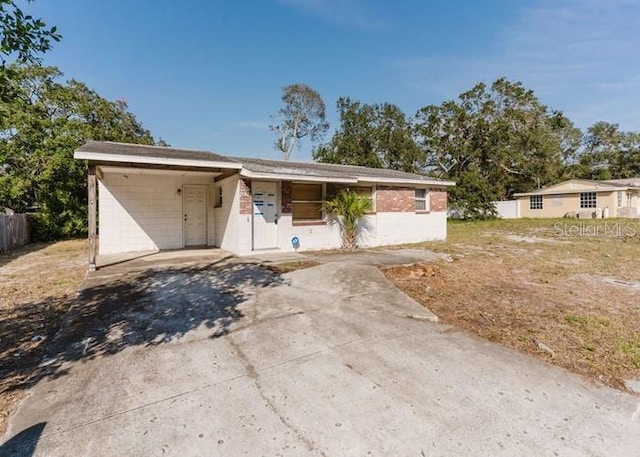 view of front of home featuring an attached carport, concrete driveway, and fence