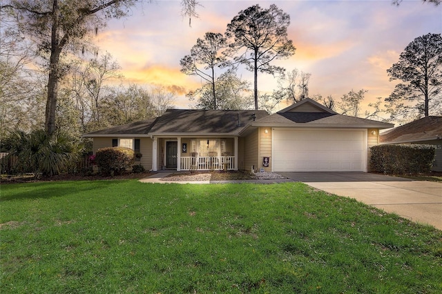 ranch-style house featuring covered porch, a lawn, an attached garage, and driveway