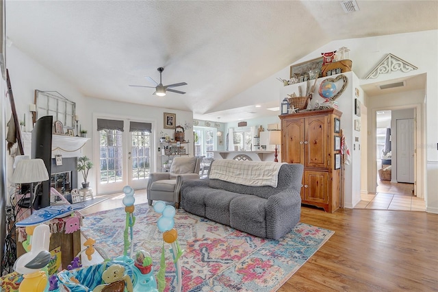 living area with a ceiling fan, vaulted ceiling, light wood-style floors, and visible vents