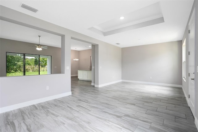 spare room featuring baseboards, visible vents, a tray ceiling, recessed lighting, and ceiling fan with notable chandelier