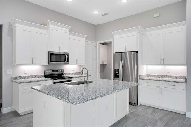 kitchen with visible vents, a center island with sink, a sink, stainless steel appliances, and white cabinets