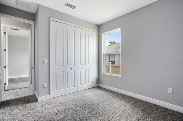 unfurnished bedroom with a closet, carpet flooring, baseboards, and visible vents