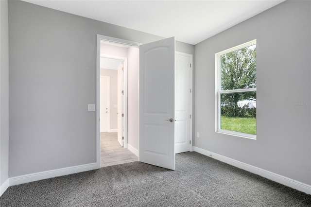 unfurnished bedroom with multiple windows, baseboards, and carpet floors