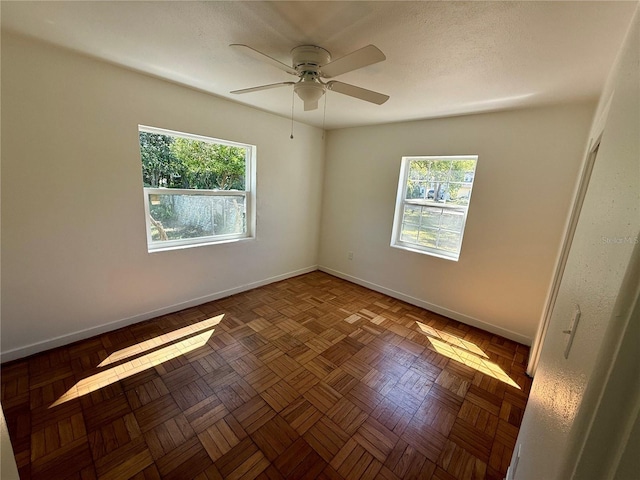 empty room with a ceiling fan and baseboards