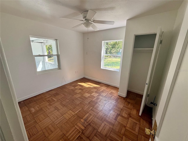 unfurnished bedroom featuring a closet, a textured ceiling, baseboards, and a ceiling fan
