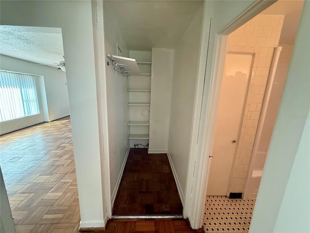 hallway featuring a textured ceiling and baseboards