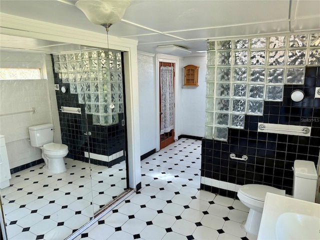bathroom featuring walk in shower, toilet, tile walls, and a sink
