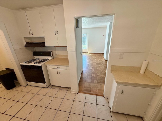 kitchen with white range with gas cooktop, under cabinet range hood, tasteful backsplash, white cabinets, and light countertops