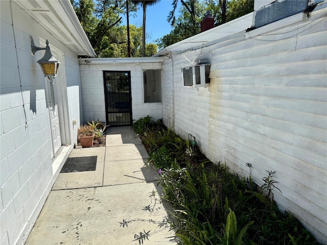 entrance to property featuring concrete block siding and a patio area