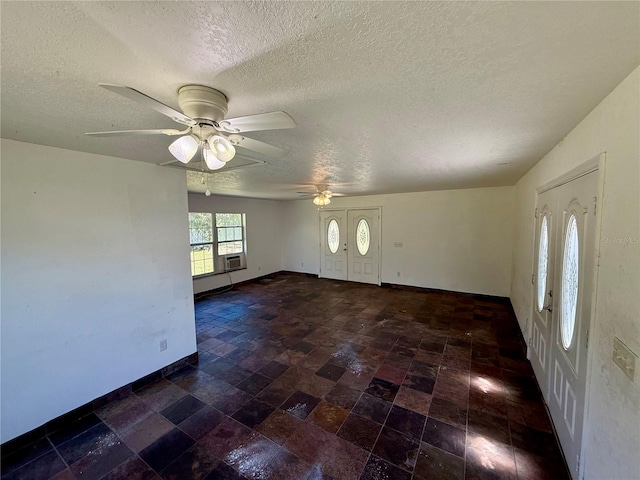interior space featuring a textured ceiling, cooling unit, baseboards, and a ceiling fan