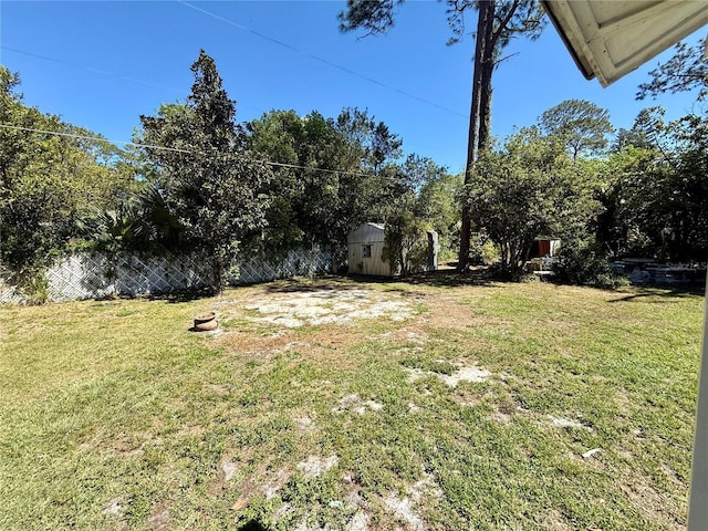 view of yard with fence, an outdoor structure, and a shed
