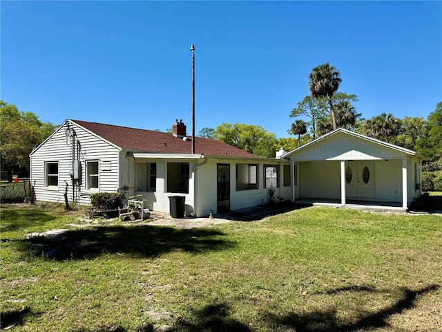 rear view of house featuring a yard, concrete block siding, and a chimney