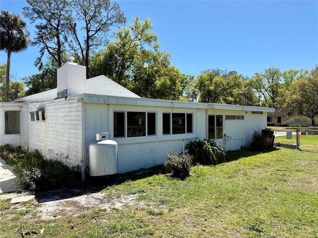 exterior space featuring a chimney, a front lawn, and fence