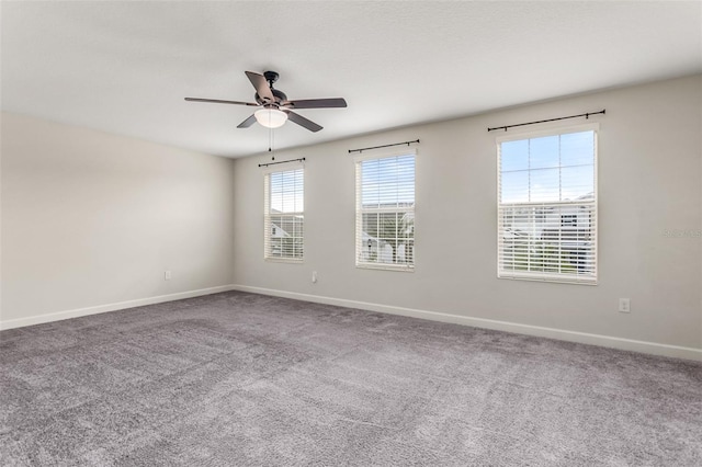 empty room with carpet floors, a ceiling fan, and baseboards