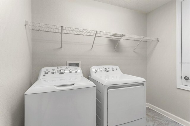 washroom with laundry area, washing machine and dryer, and baseboards