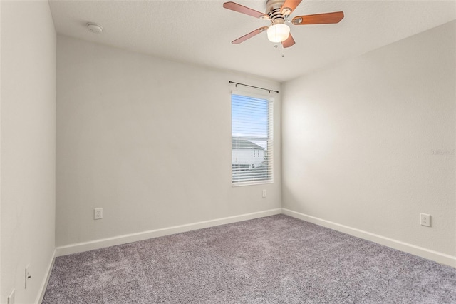 carpeted spare room with a ceiling fan and baseboards