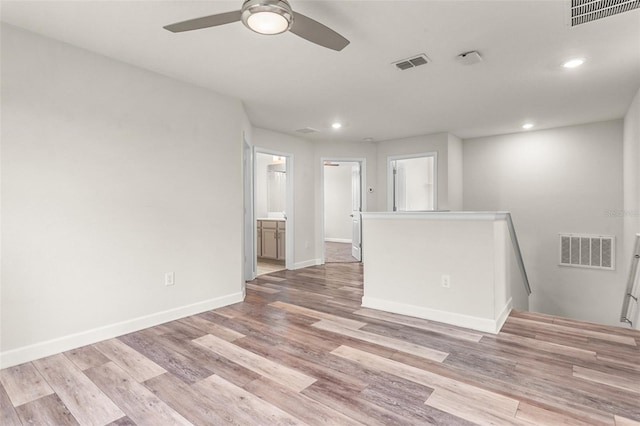 empty room featuring light wood-style flooring, visible vents, and baseboards