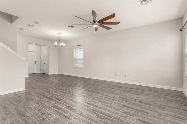 empty room with ceiling fan with notable chandelier, visible vents, baseboards, and wood finished floors