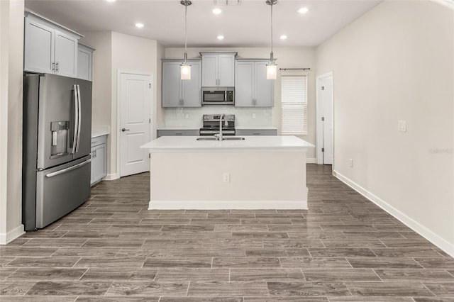 kitchen featuring stainless steel appliances, wood tiled floor, light countertops, and gray cabinetry