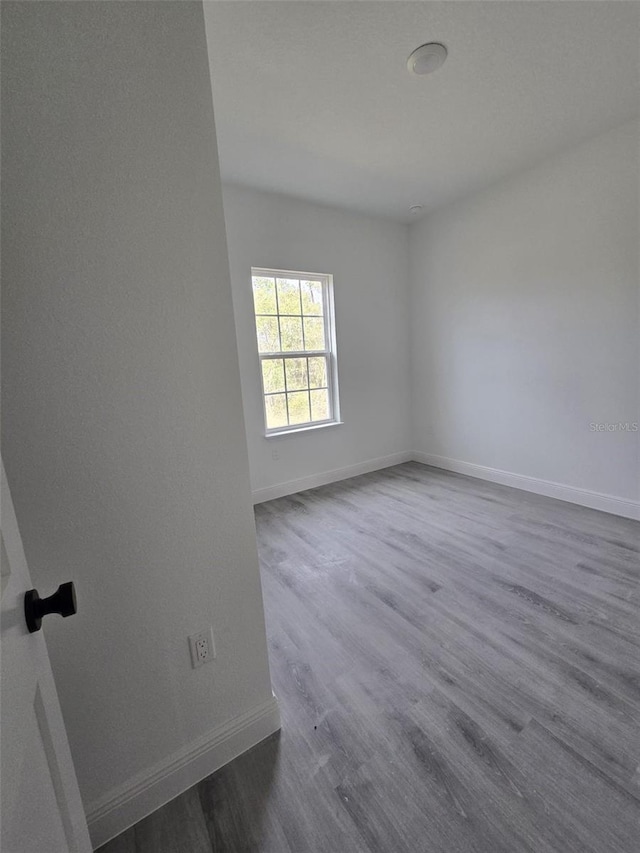 spare room featuring dark wood-style floors and baseboards