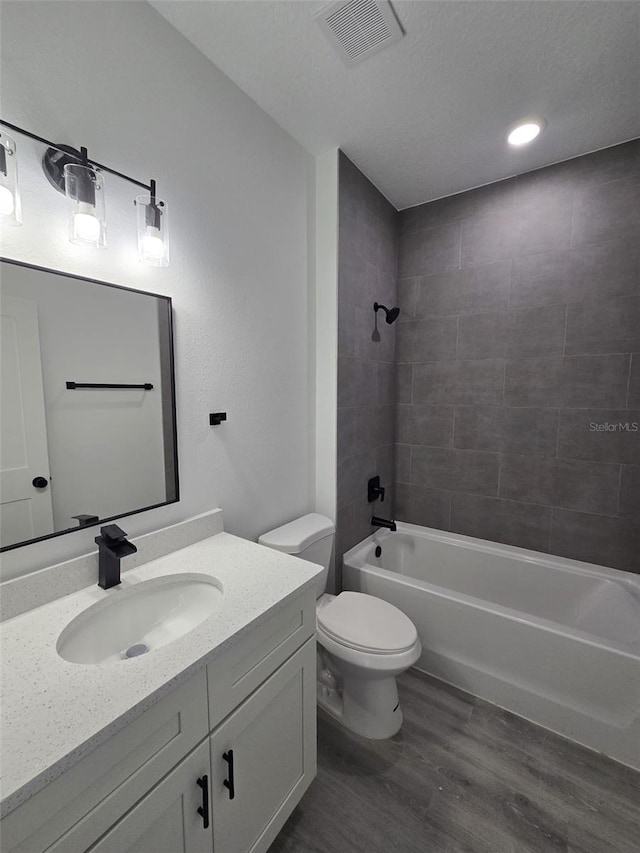 bathroom with shower / tub combination, toilet, wood finished floors, vanity, and visible vents