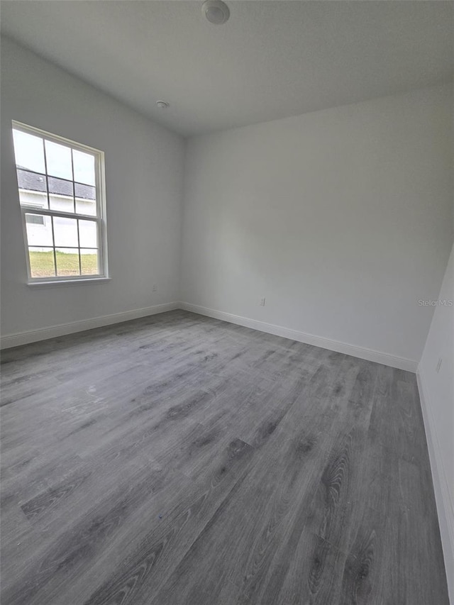 empty room featuring dark wood-type flooring and baseboards