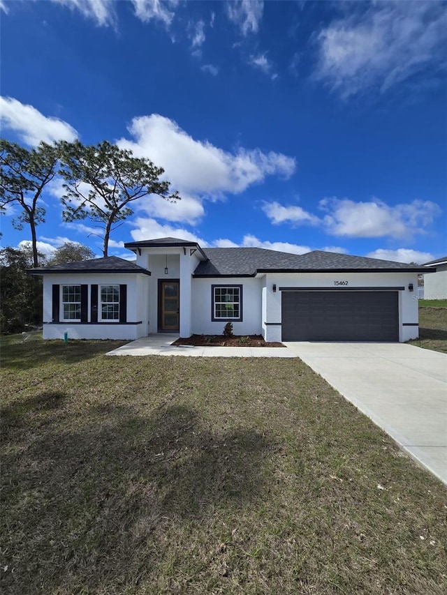 prairie-style home featuring a garage, a front yard, driveway, and stucco siding