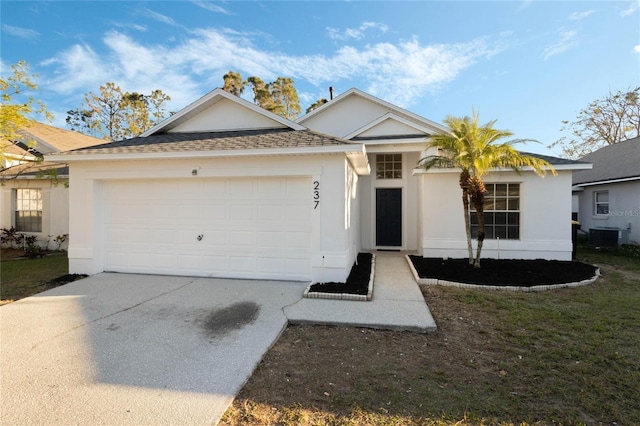 ranch-style home with a garage, concrete driveway, a shingled roof, and stucco siding