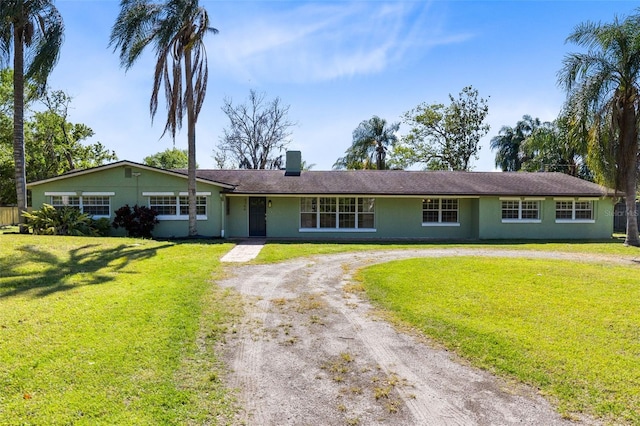 ranch-style home with a front yard, a chimney, and dirt driveway